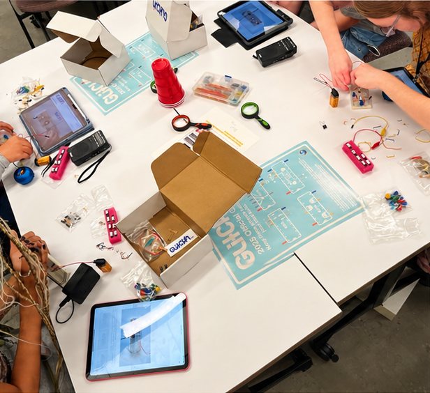 Seen from above: a table with kits, tablets playing the lessons, and breadboards in progress